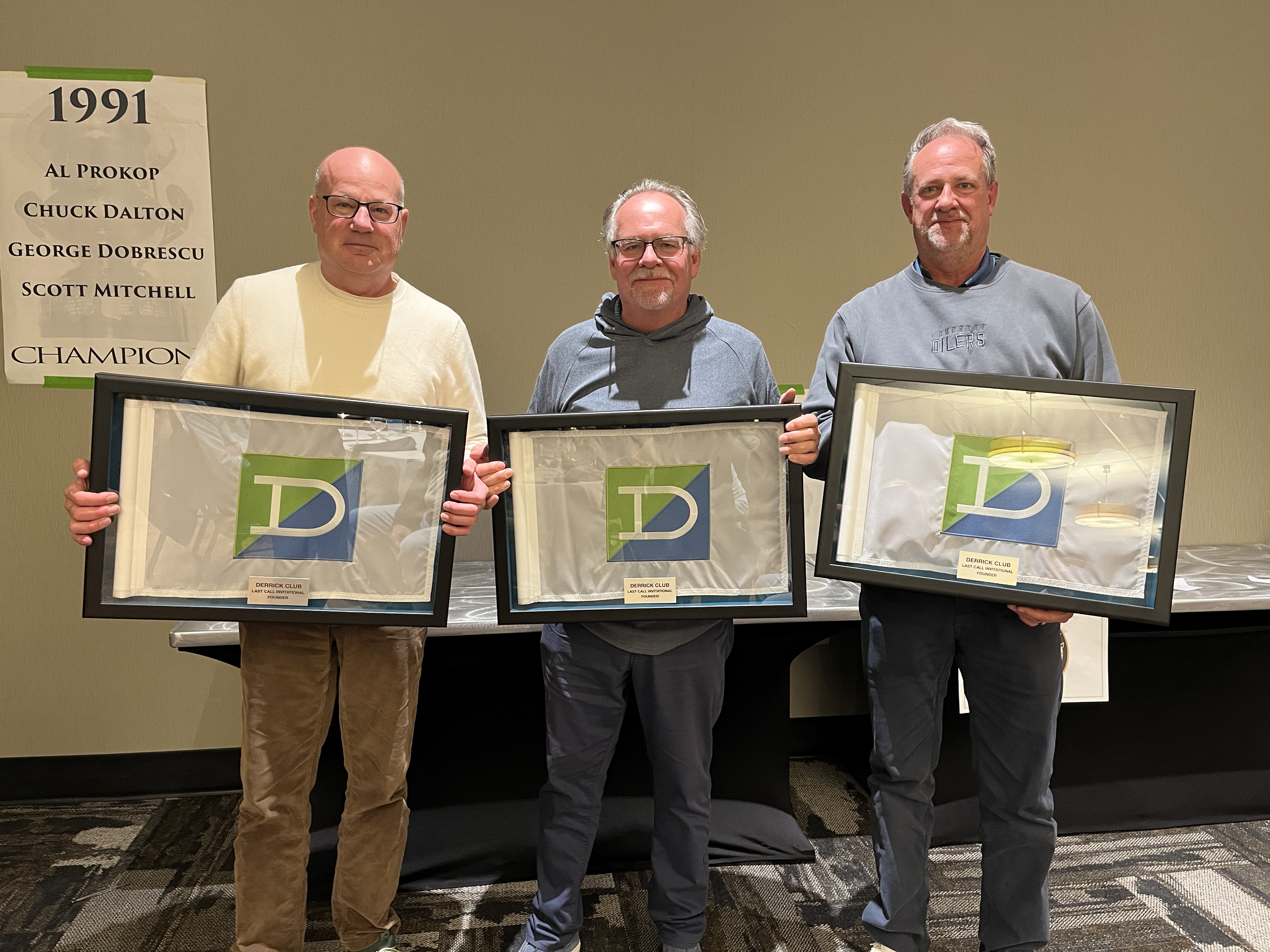 The Last Call founders — Bruce Comeau, Scott Lindsay and Craig Lindsay — with their framed Derrick Club founder flags at the 40th